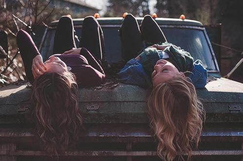 twee jonge vrouwen relaxen op een roestige oude auto